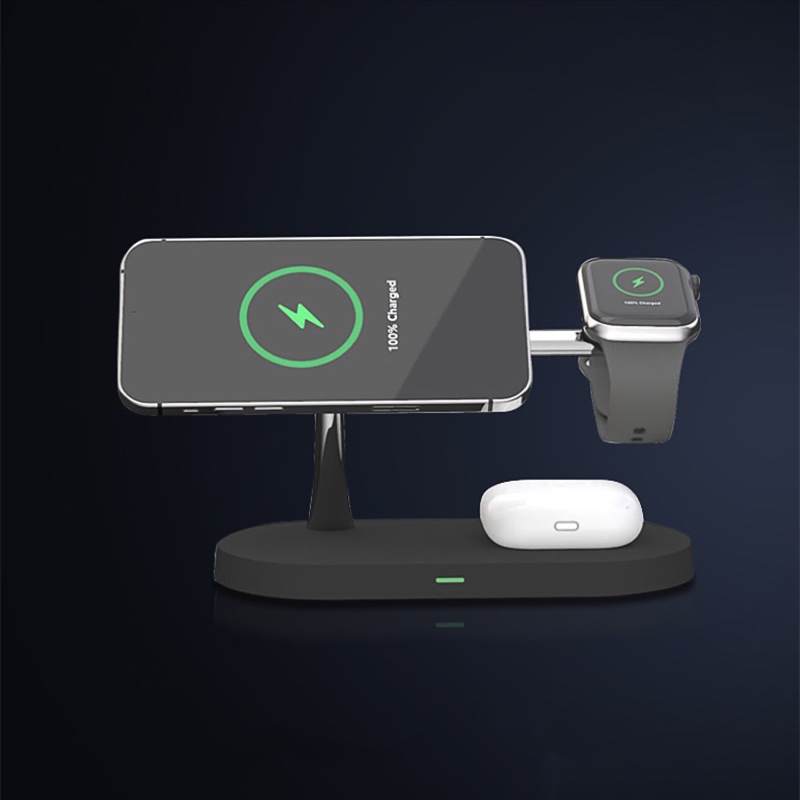 Fourfold Halo Dock in black on a dark background with a phone, a watch and earbuds charging on it