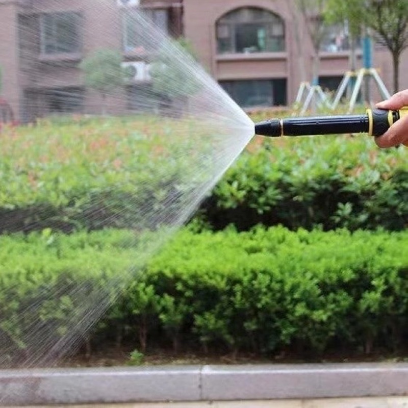 Fourfold Jetstream held at the end of a hose, spraying a wide fan of water over a garden hedge