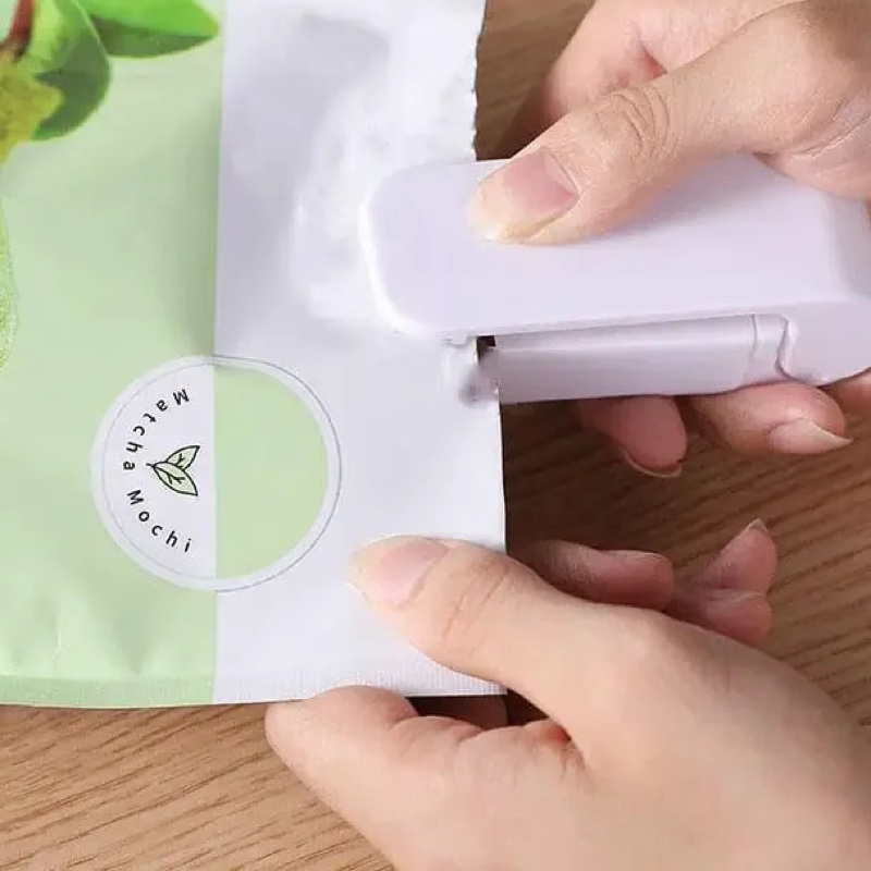 Fourfold Pinch sealing a green pouch, held between two hands