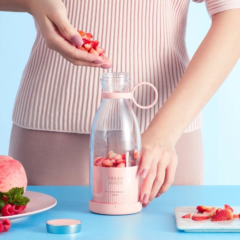Strawberries being dropped into the pink Fourfold Whirl 350 on a kitchen table